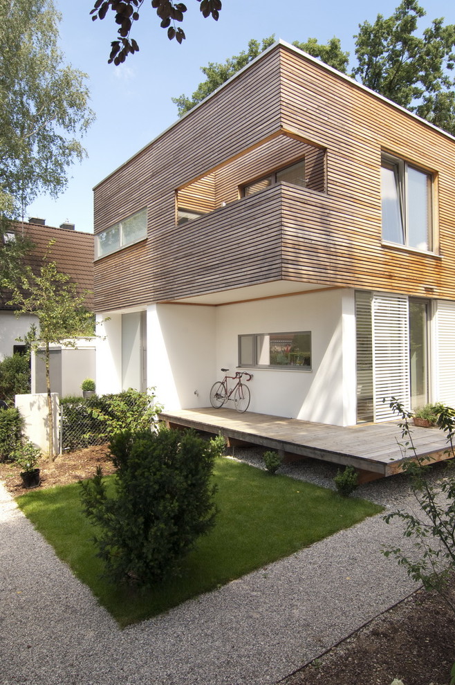 Design ideas for a mid-sized contemporary two-storey exterior in Munich with wood siding and a flat roof.