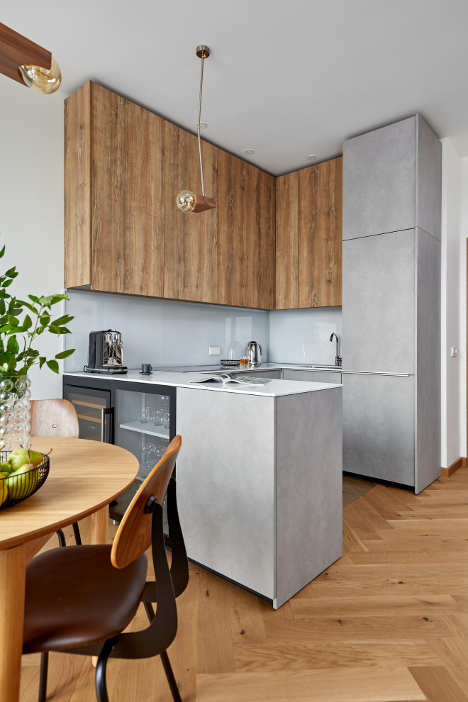 Design ideas for a small u-shaped open plan kitchen in Moscow with a single-bowl sink, grey cabinets, solid surface benchtops, white splashback, glass sheet splashback, panelled appliances, no island and white benchtop.