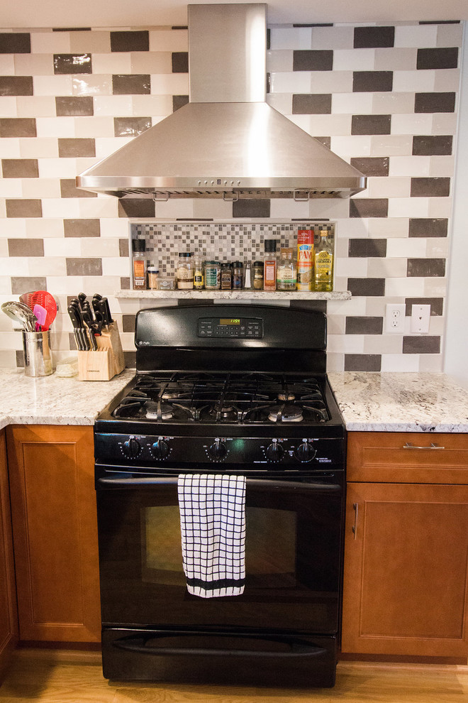 Eat-in kitchen - mid-sized transitional u-shaped medium tone wood floor eat-in kitchen idea in Boston with an undermount sink, recessed-panel cabinets, medium tone wood cabinets, granite countertops, multicolored backsplash, subway tile backsplash, black appliances and a peninsula