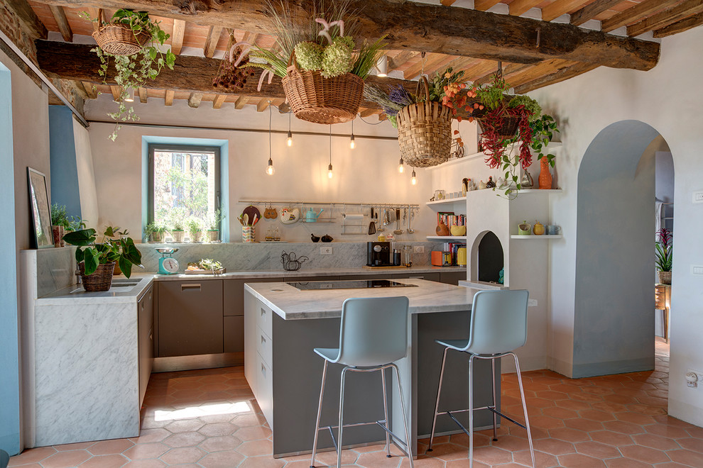 Design ideas for a mediterranean separate kitchen in Other with flat-panel cabinets, grey cabinets, grey splashback, stone slab splashback, terra-cotta floors, with island, orange floor, grey benchtop and exposed beam.
