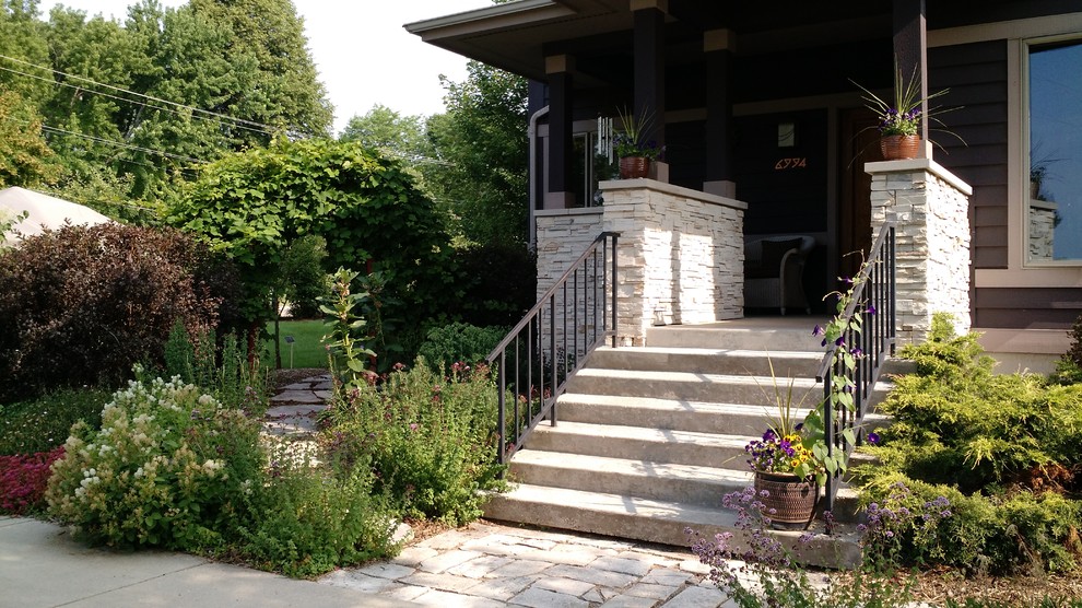 This is an example of a small arts and crafts front yard full sun garden for summer in Other with natural stone pavers.