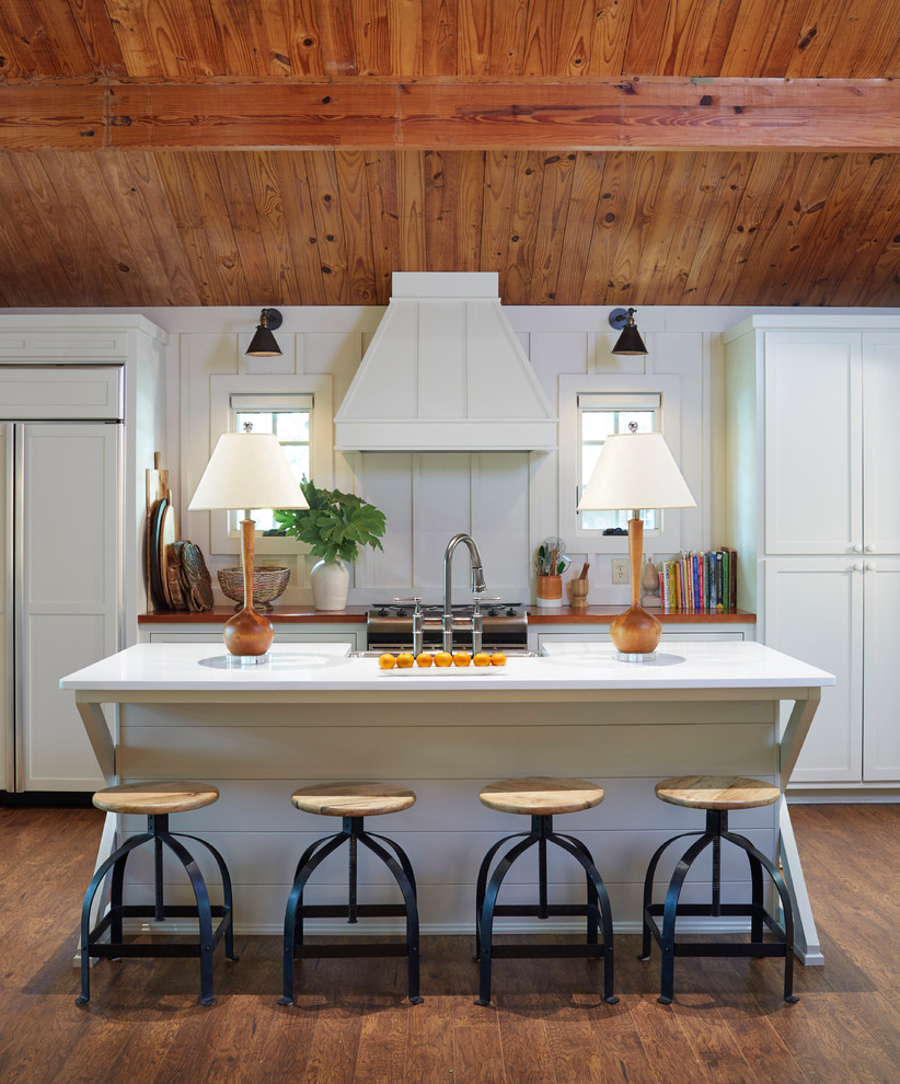This is an example of a mid-sized country galley kitchen in Birmingham with a farmhouse sink, shaker cabinets, white cabinets, wood benchtops, panelled appliances, dark hardwood floors, with island and brown floor.