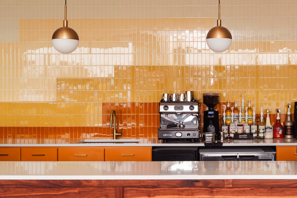 Exemple d'une grande cuisine ouverte linéaire moderne avec un évier posé, des portes de placard oranges, une crédence jaune, une crédence en carreau de verre et un électroménager en acier inoxydable.