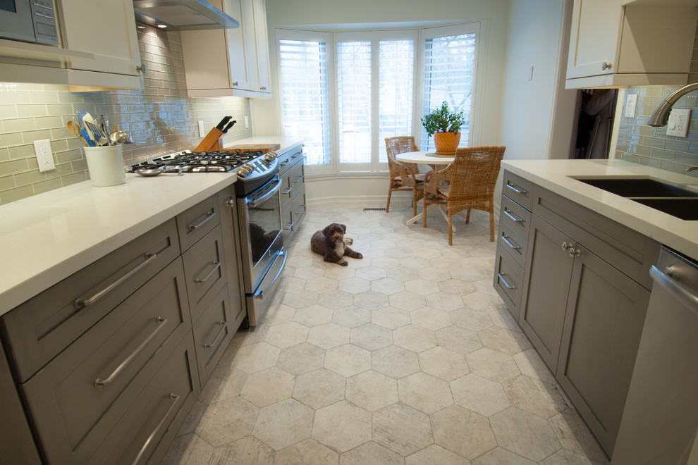 Inspiration for a mid-sized transitional galley ceramic tile enclosed kitchen remodel in Toronto with shaker cabinets, white cabinets, quartzite countertops, gray backsplash, glass tile backsplash, stainless steel appliances and no island