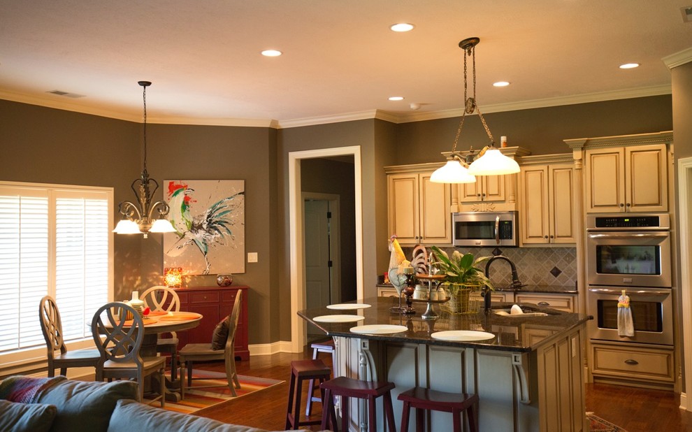 Mid-sized transitional l-shaped medium tone wood floor open concept kitchen photo in Chicago with raised-panel cabinets, beige cabinets, laminate countertops, beige backsplash, ceramic backsplash, stainless steel appliances, an island and an undermount sink