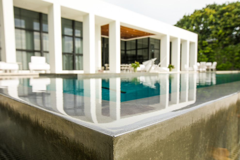 Photo of an expansive contemporary backyard rectangular lap pool in Miami with a water feature and natural stone pavers.