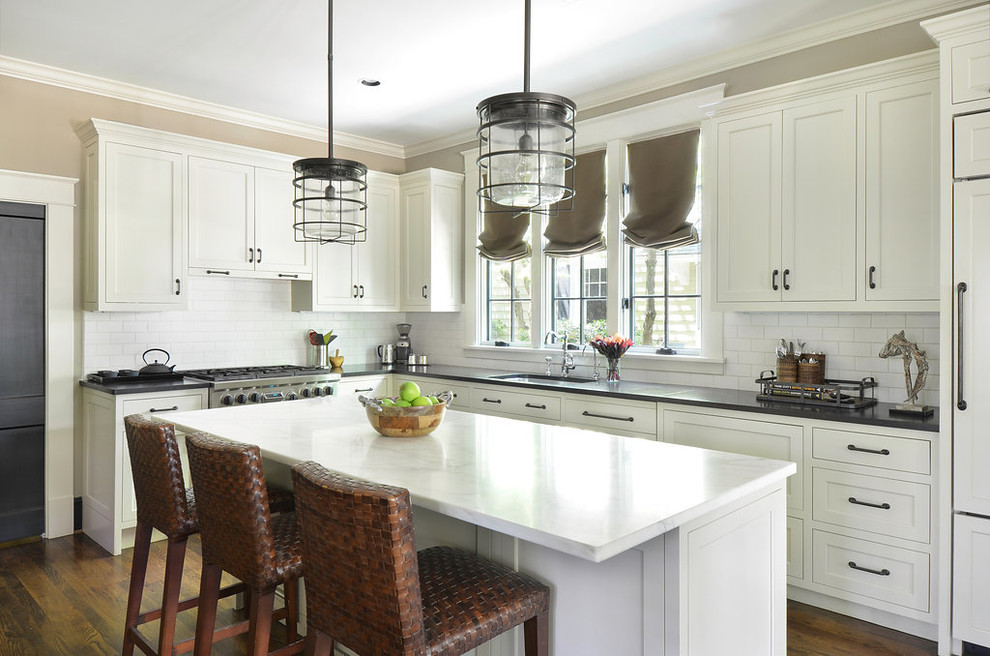 Inspiration for a traditional l-shaped kitchen in Atlanta with an undermount sink, shaker cabinets, white cabinets, white splashback, subway tile splashback, stainless steel appliances, medium hardwood floors, with island and marble benchtops.