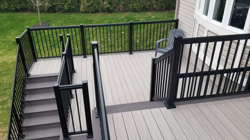 Photo of a large modern backyard and first floor deck in Ottawa with no cover and metal railing.