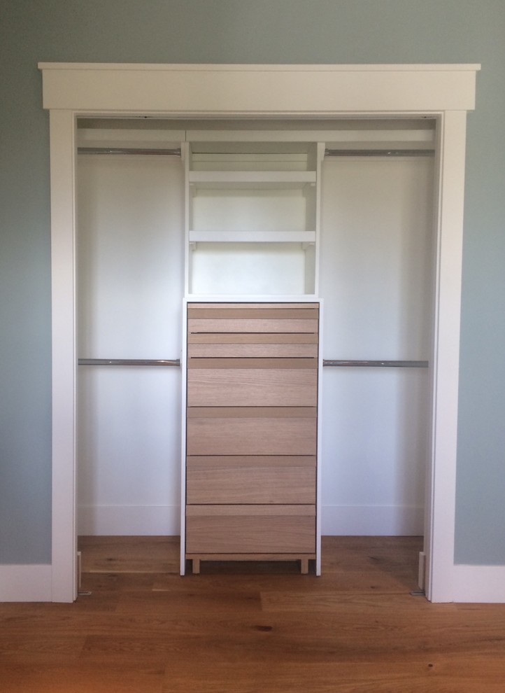 Photo of a mid-sized traditional gender-neutral built-in wardrobe in Calgary with medium hardwood floors.