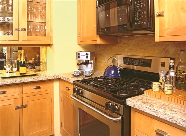 Photo of a small arts and crafts u-shaped separate kitchen in Phoenix with an undermount sink, glass-front cabinets, light wood cabinets, granite benchtops, mirror splashback, stainless steel appliances, bamboo floors and no island.