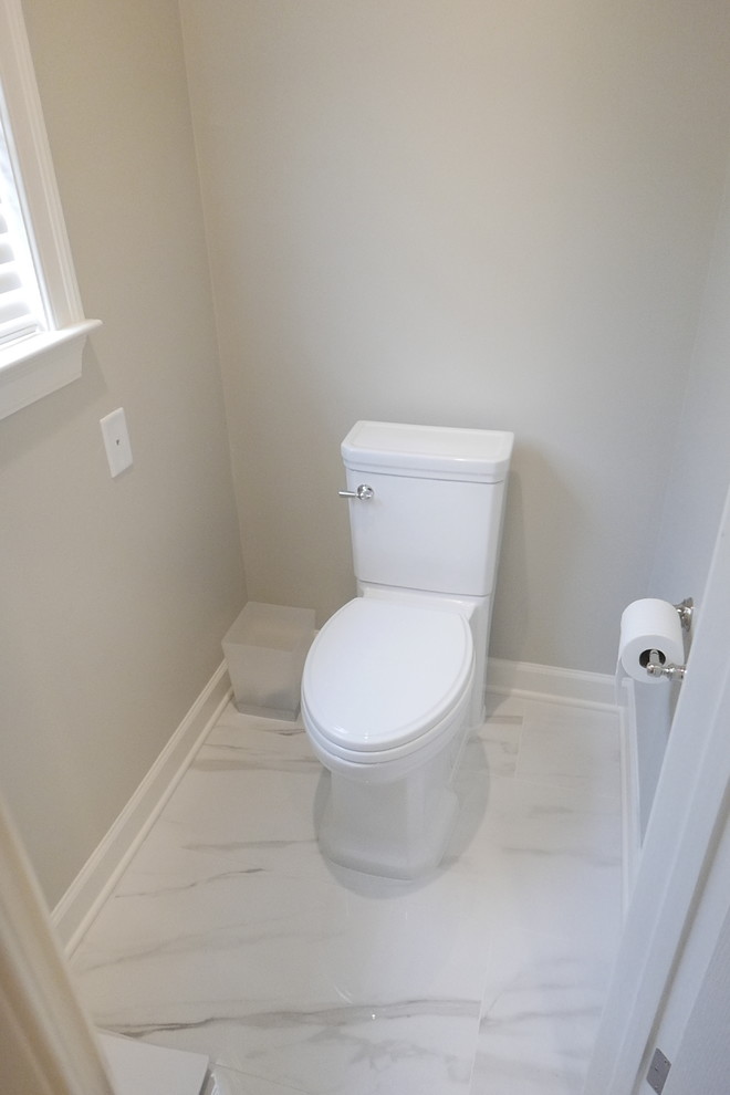 Large transitional master white tile and porcelain tile porcelain tile and white floor freestanding bathtub photo with shaker cabinets, white cabinets, a two-piece toilet, beige walls, an undermount sink, marble countertops, a hinged shower door and white countertops