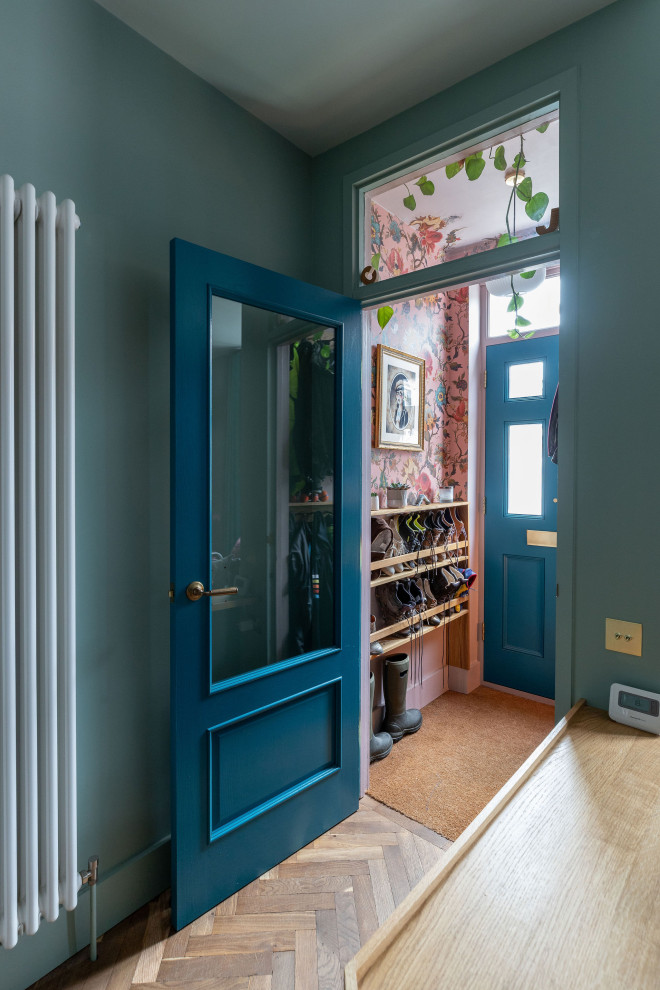 Inredning av en liten ingång och ytterdörr, med rosa väggar, mörkt trägolv, en enkeldörr, en blå dörr och brunt golv