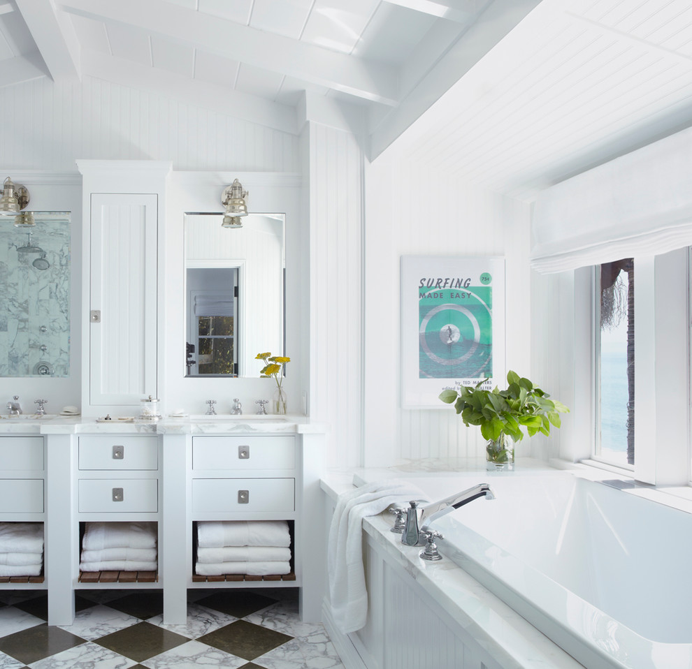 Design ideas for a beach style master bathroom in Los Angeles with white cabinets, a drop-in tub, white walls and flat-panel cabinets.