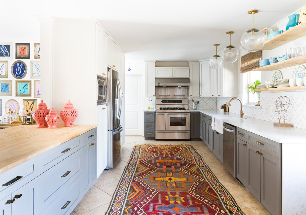 Design ideas for a mid-sized eclectic galley open plan kitchen with an undermount sink, shaker cabinets, grey cabinets, quartz benchtops, white splashback, porcelain splashback, stainless steel appliances, limestone floors, a peninsula, brown floor and white benchtop.