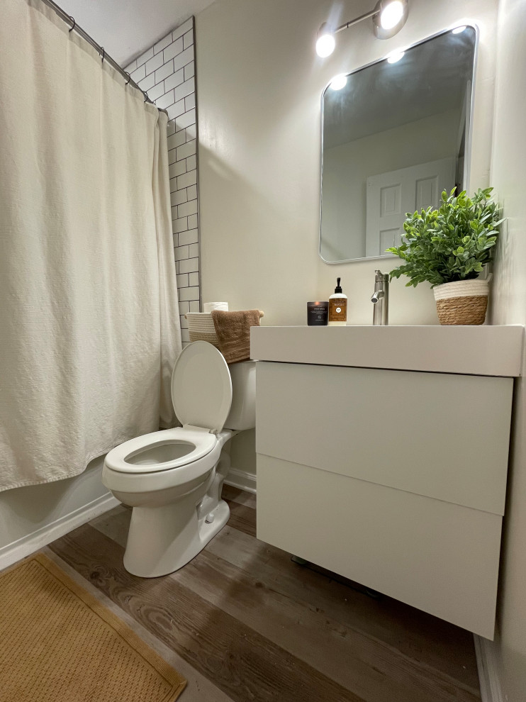 Design ideas for a small retro family bathroom in St Louis with flat-panel cabinets, white cabinets, an alcove bath, an alcove shower, a one-piece toilet, white tiles, metro tiles, beige walls, wood-effect flooring, an integrated sink, solid surface worktops, brown floors, a shower curtain, white worktops, a wall niche, a single sink and a floating vanity unit.