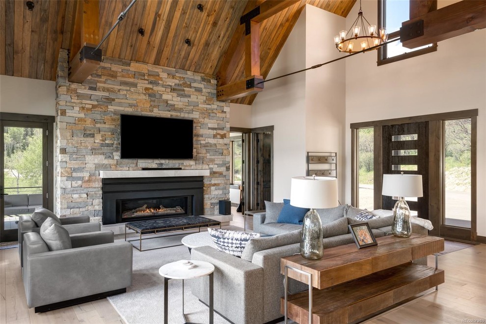 Photo of a mid-sized country open concept family room in Denver with white walls, light hardwood floors, a standard fireplace, a metal fireplace surround and a wall-mounted tv.