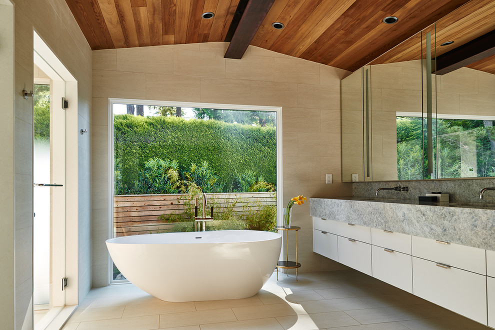 This is an example of a large midcentury master bathroom in Seattle with flat-panel cabinets, white cabinets, a freestanding tub, beige tile, a double shower, porcelain tile, beige walls, porcelain floors, an undermount sink, marble benchtops and grey benchtops.