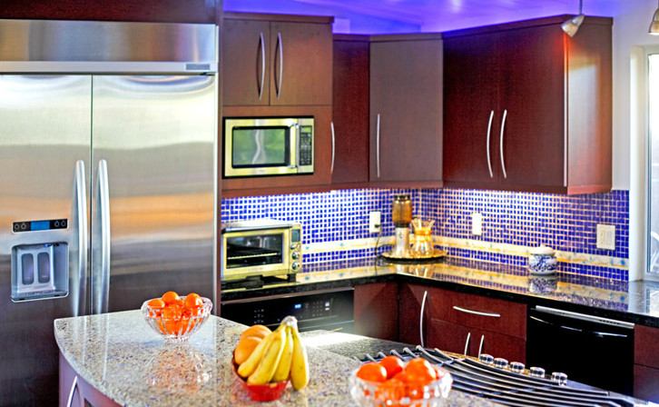 Example of a mid-sized transitional single-wall limestone floor and brown floor eat-in kitchen design with a drop-in sink, medium tone wood cabinets, blue backsplash, stainless steel appliances, an island, flat-panel cabinets, granite countertops and mosaic tile backsplash
