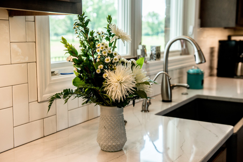 Open concept kitchen - large transitional l-shaped vinyl floor and multicolored floor open concept kitchen idea with a farmhouse sink, shaker cabinets, gray cabinets, quartz countertops, white backsplash, subway tile backsplash, stainless steel appliances, an island and white countertops