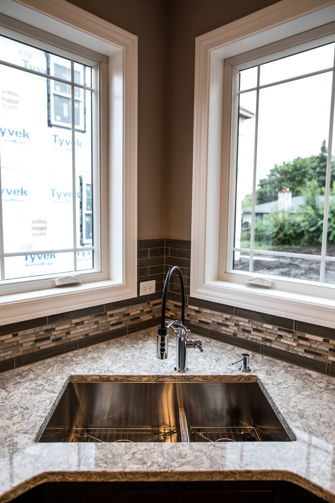 Inspiration for a mid-sized transitional l-shaped dark wood floor home design remodel in Chicago with an undermount sink, shaker cabinets, brown cabinets, granite countertops, gray backsplash, subway tile backsplash, stainless steel appliances and an island