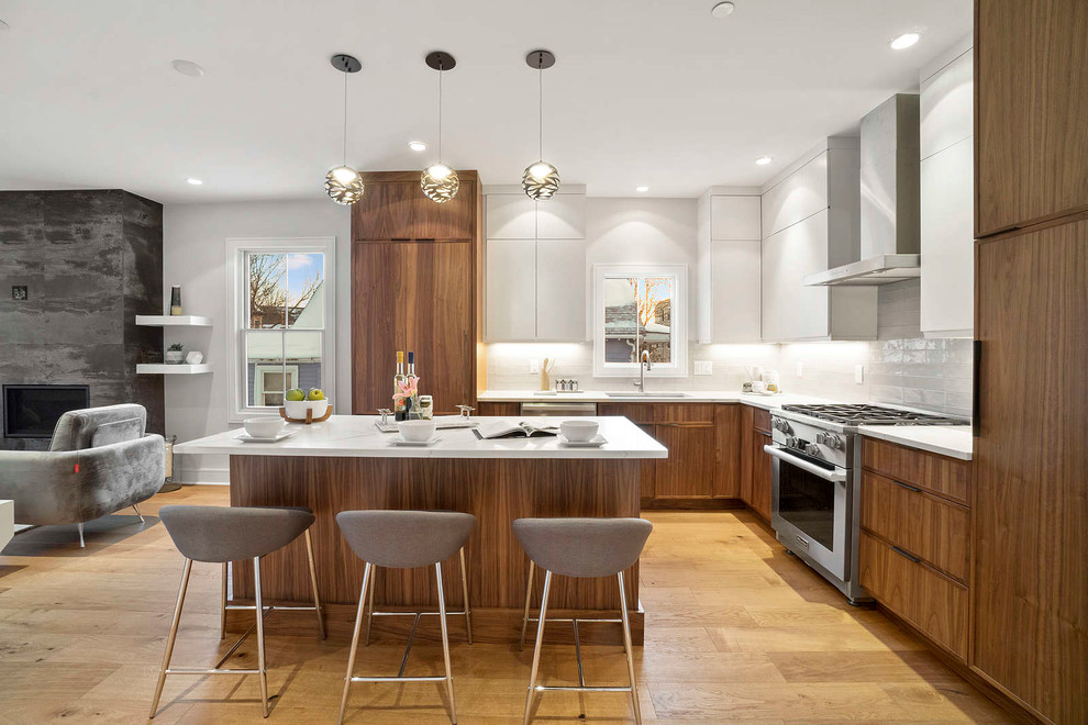 Design ideas for a mid-sized contemporary l-shaped open plan kitchen in Boston with flat-panel cabinets, brown cabinets, quartzite benchtops, white splashback, ceramic splashback, stainless steel appliances, medium hardwood floors, with island, brown floor, white benchtop and an undermount sink.