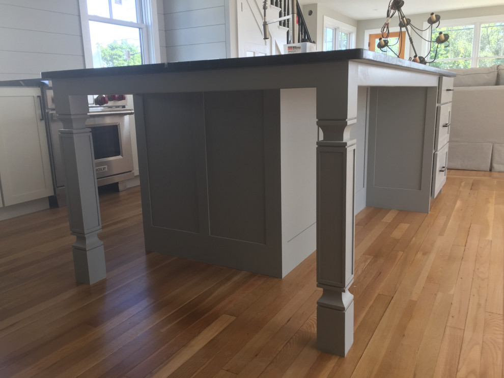 Mid-sized transitional galley kitchen in Portland Maine with flat-panel cabinets, soapstone benchtops, shiplap splashback, stainless steel appliances, medium hardwood floors and black benchtop.
