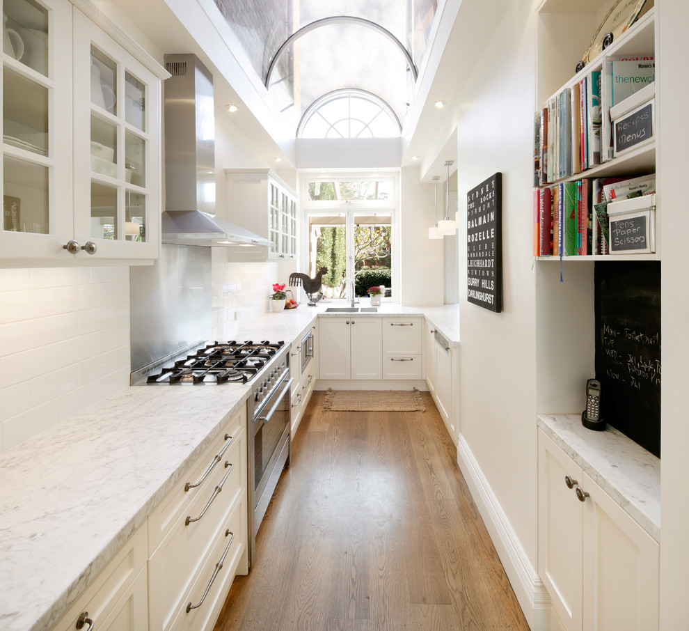 Inspiration for a mid-sized traditional u-shaped separate kitchen in Sydney with shaker cabinets, marble benchtops, an undermount sink, white cabinets, white splashback, subway tile splashback, stainless steel appliances, medium hardwood floors and no island.