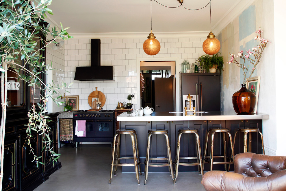 Large eclectic single-wall kitchen in Malmo with a drop-in sink, recessed-panel cabinets, black cabinets, black appliances, concrete floors and with island.