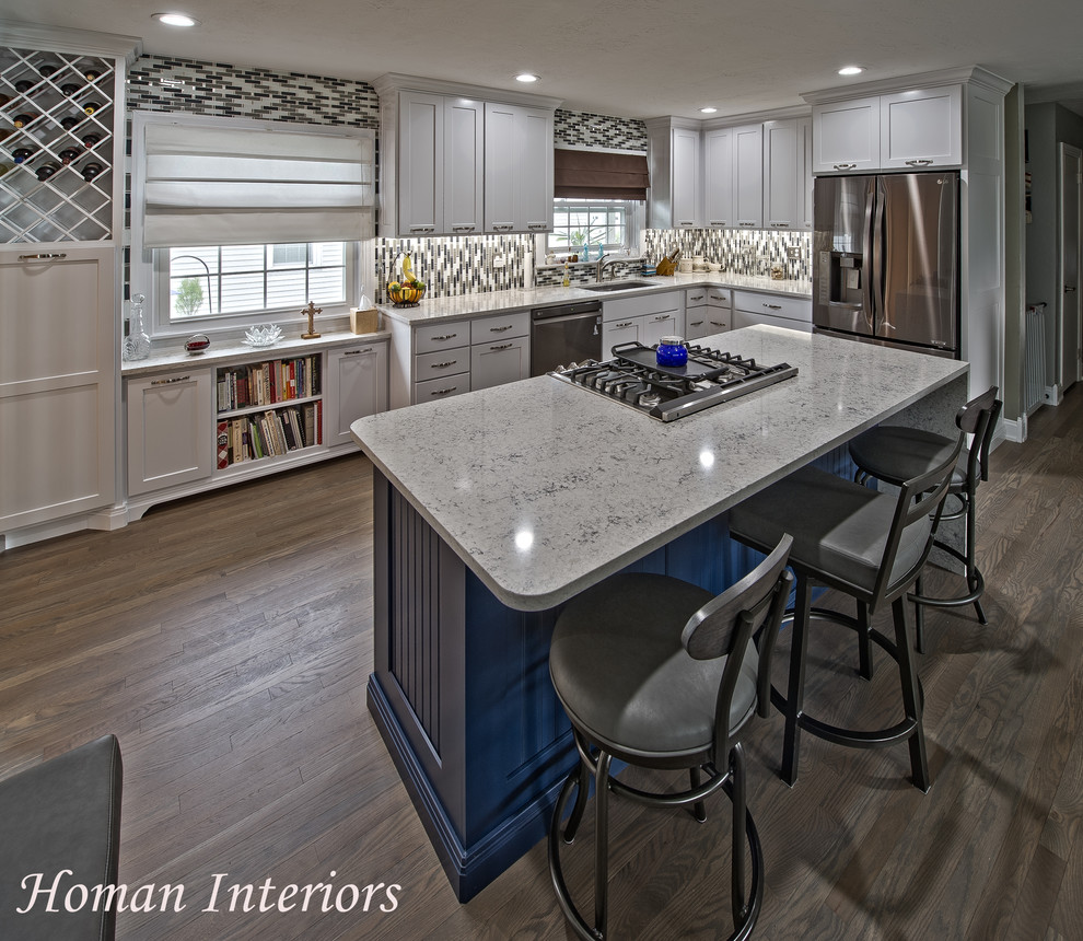 This is an example of a mid-sized traditional l-shaped eat-in kitchen in Other with a double-bowl sink, flat-panel cabinets, white cabinets, quartz benchtops, multi-coloured splashback, glass tile splashback, stainless steel appliances, vinyl floors, with island, grey floor and white benchtop.