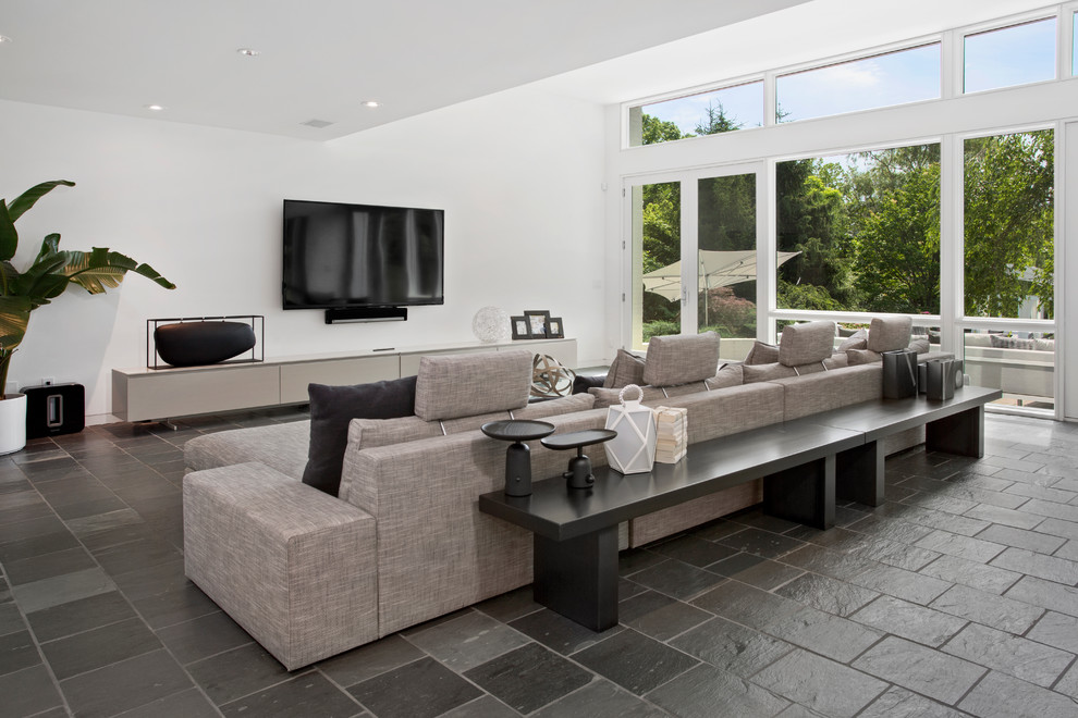 Large contemporary open concept family room in Cincinnati with white walls, slate floors and a wall-mounted tv.