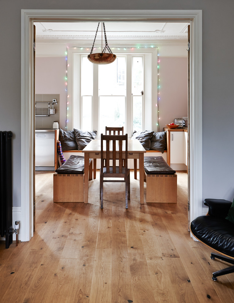This is an example of a mid-sized eclectic dining room in London with medium hardwood floors and pink walls.