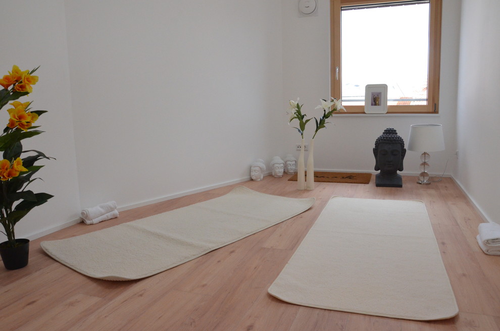 Photo of a small asian home yoga studio in Nuremberg with white walls, light hardwood floors and beige floor.