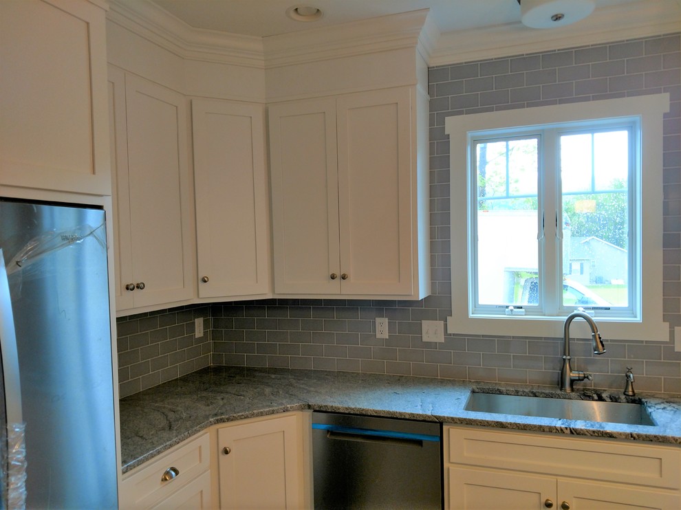 Inspiration for a mid-sized transitional l-shaped home design remodel with an undermount sink, recessed-panel cabinets, white cabinets, gray backsplash, subway tile backsplash, stainless steel appliances, an island and multicolored countertops