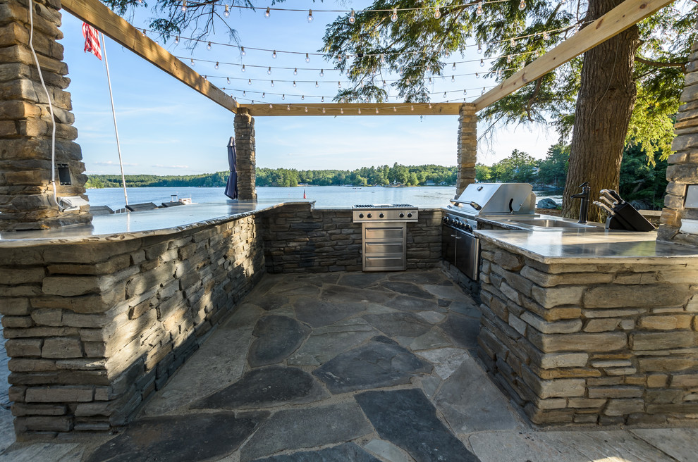 Mid-sized country backyard patio in Other with an outdoor kitchen, natural stone pavers and no cover.