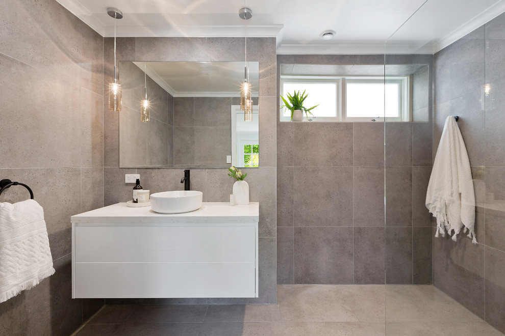 This is an example of a mid-sized contemporary 3/4 bathroom in Sydney with an open shower, gray tile, ceramic tile, grey walls, ceramic floors, grey floor, an open shower, flat-panel cabinets, white cabinets, a vessel sink and white benchtops.