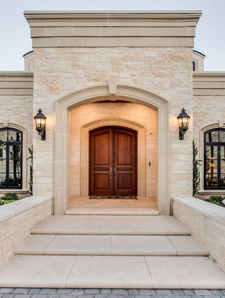 This is an example of a large mediterranean two-storey beige house exterior in Austin with stone veneer, a hip roof and a metal roof.