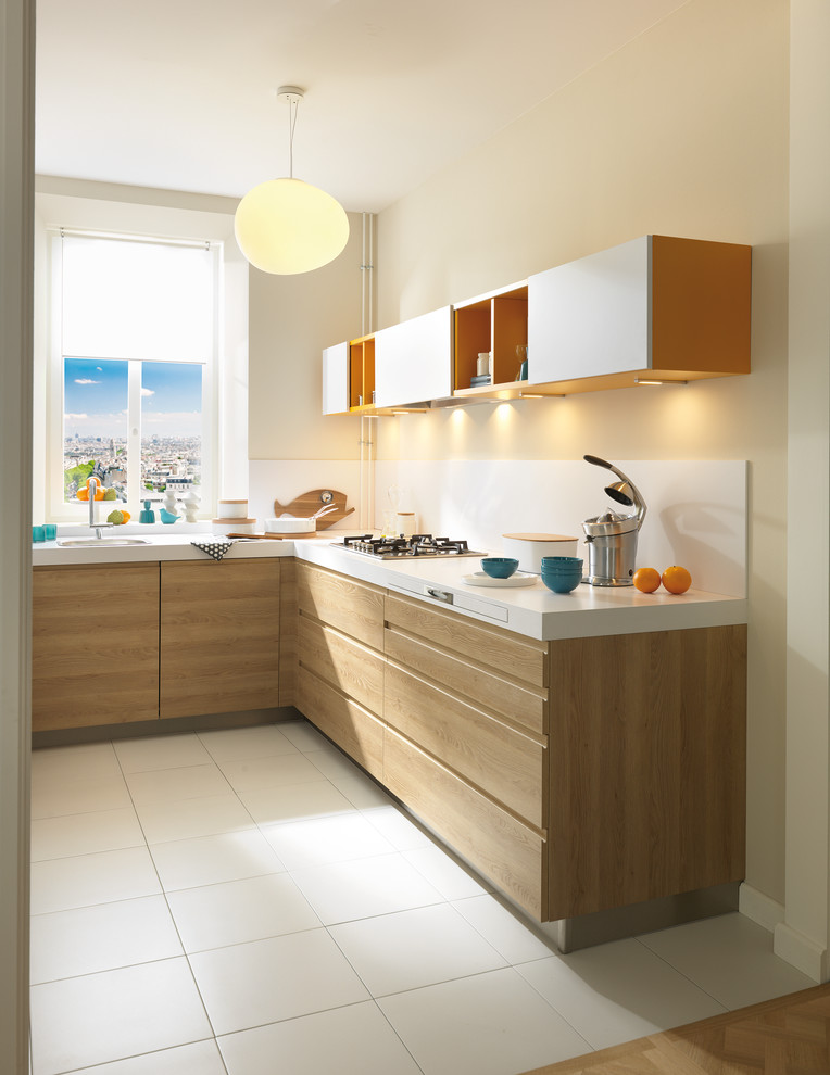 Inspiration for a small contemporary l-shaped kitchen in London with a single-bowl sink, white splashback, glass sheet splashback, stainless steel appliances, ceramic floors and light wood cabinets.