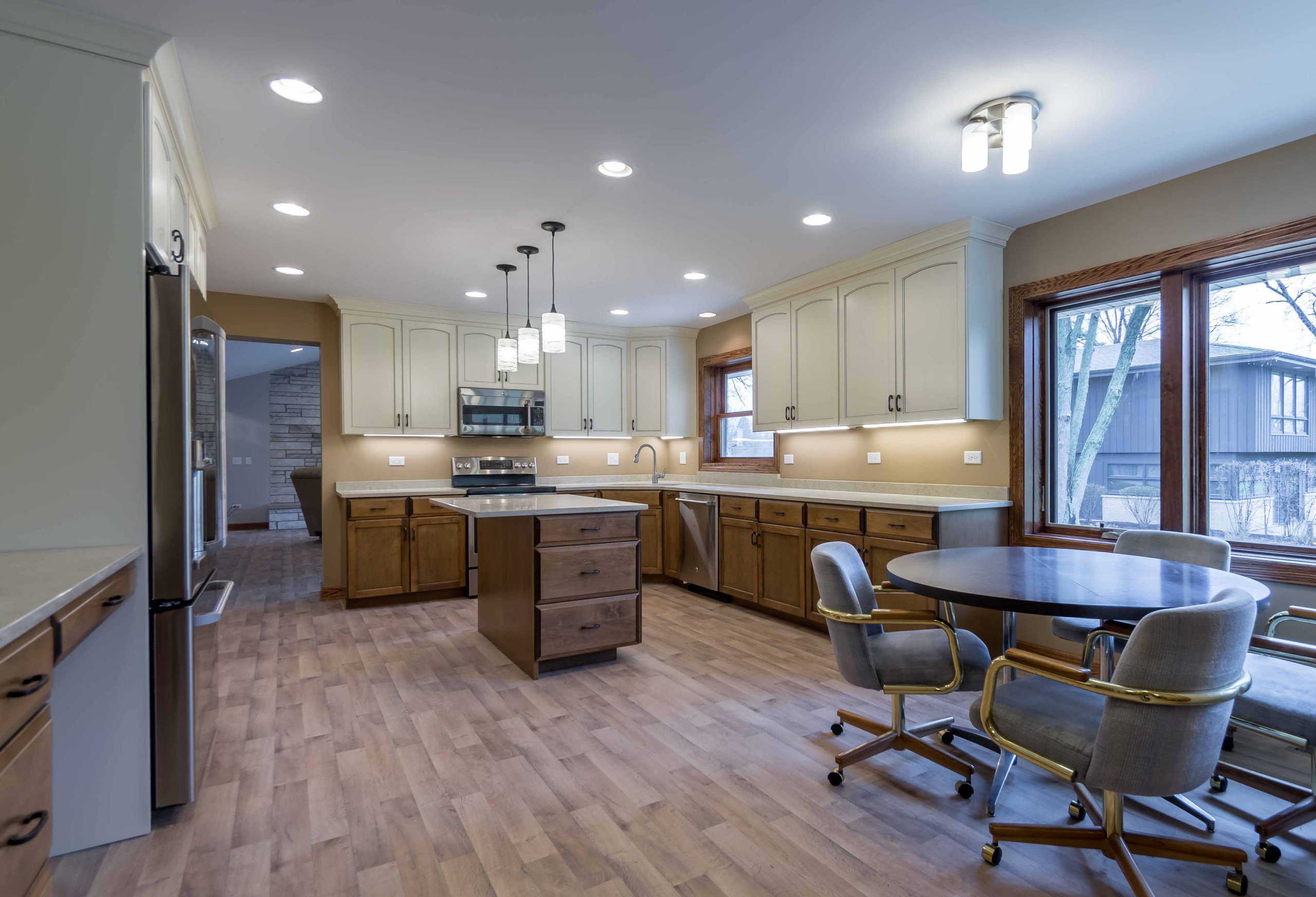 Example of a mid-sized classic l-shaped light wood floor, beige floor and wallpaper ceiling eat-in kitchen design in Chicago with a triple-bowl sink, recessed-panel cabinets, white cabinets, onyx coun