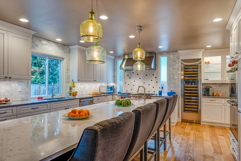 Large transitional u-shaped light wood floor eat-in kitchen photo in Seattle with an undermount sink, beaded inset cabinets, blue cabinets, quartz countertops, multicolored backsplash, porcelain backsplash, stainless steel appliances and an island