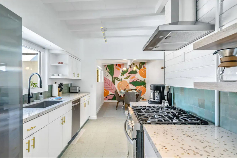Midcentury galley kitchen in Other with flat-panel cabinets, white cabinets, terrazzo benchtops, no island, multi-coloured benchtop, an undermount sink, green splashback, terra-cotta splashback, stainless steel appliances, laminate floors and blue floor.