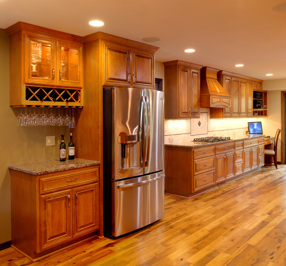 This is an example of a mid-sized traditional galley eat-in kitchen in Minneapolis with an undermount sink, recessed-panel cabinets, dark wood cabinets, granite benchtops, white splashback, porcelain splashback, stainless steel appliances, light hardwood floors, with island and beige floor.