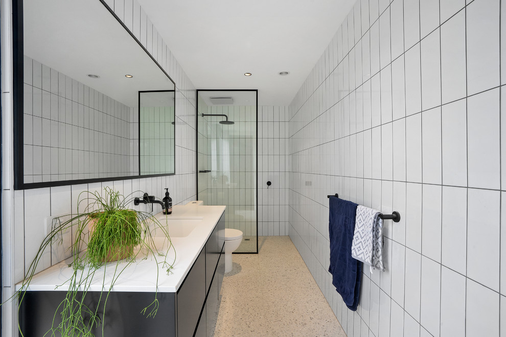 Photo of a small contemporary master bathroom in Geelong with an open shower, white tile, porcelain tile, white walls, terrazzo floors, a drop-in sink, engineered quartz benchtops, white floor, an open shower, white benchtops, flat-panel cabinets and black cabinets.