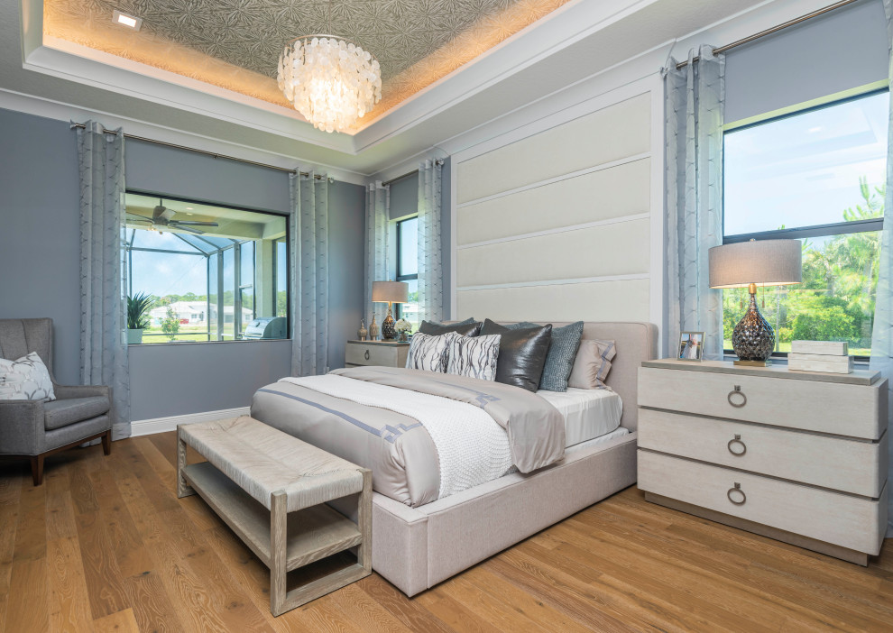 Modelo de dormitorio principal y beige tradicional renovado grande con paredes azules, suelo de madera en tonos medios, suelo marrón, papel pintado y panelado
