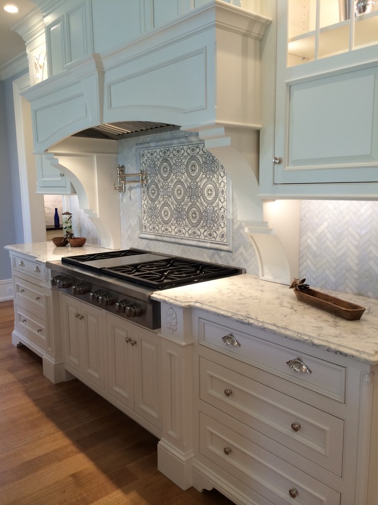 Photo of a large traditional l-shaped separate kitchen in Bridgeport with a farmhouse sink, beaded inset cabinets, white cabinets, marble benchtops, grey splashback, mosaic tile splashback, panelled appliances, light hardwood floors, with island and brown floor.