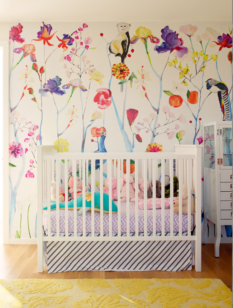 Photo of a small contemporary nursery for girls in Seattle with multi-coloured walls and medium hardwood floors.