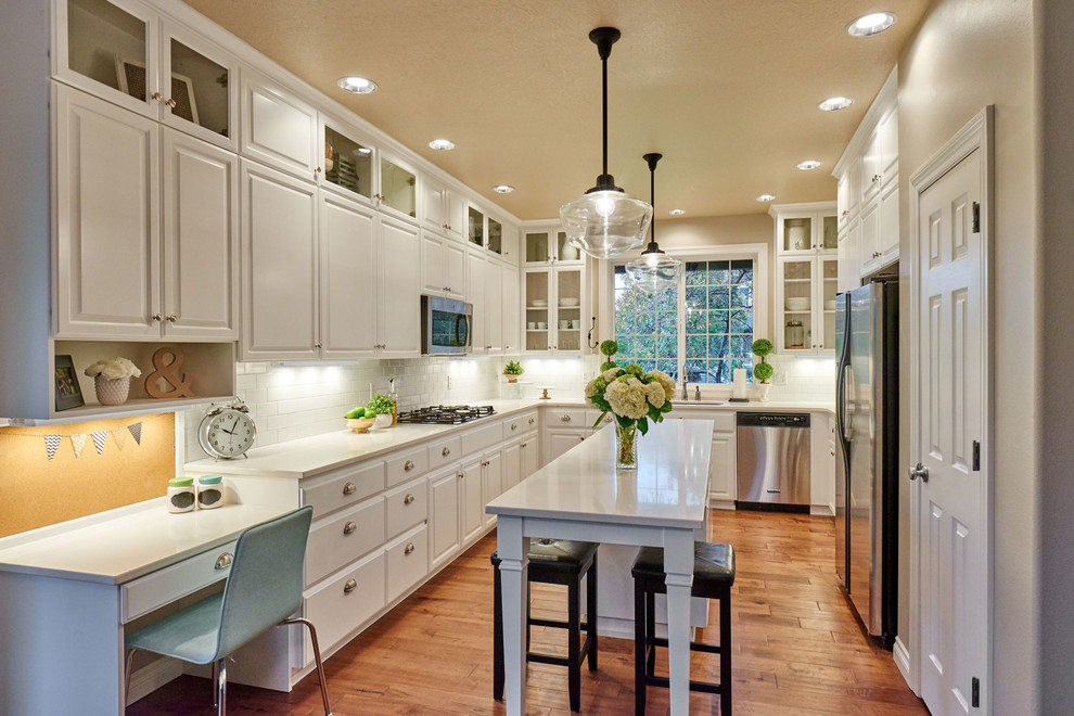 Inspiration for a mid-sized traditional u-shaped eat-in kitchen in Portland with an undermount sink, raised-panel cabinets, white cabinets, white splashback, subway tile splashback, stainless steel appliances, medium hardwood floors, with island and quartz benchtops.