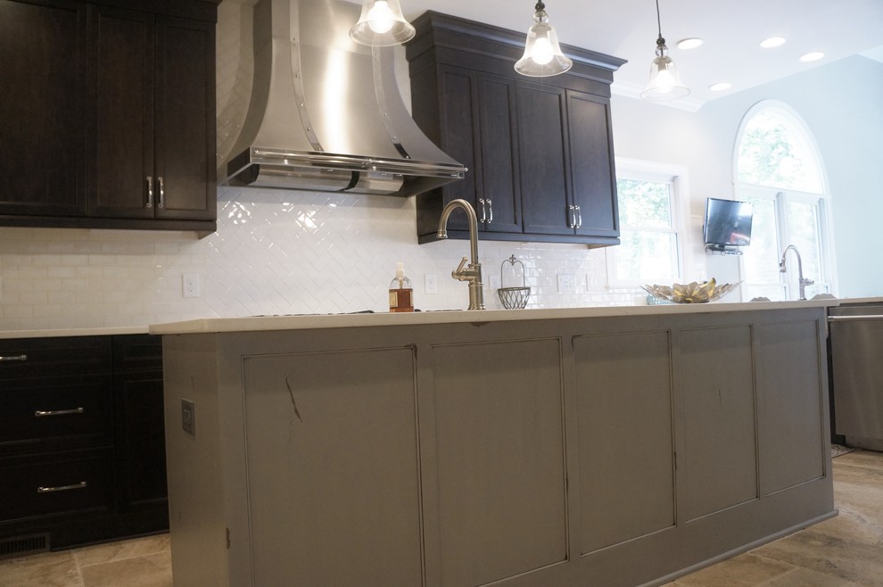 Eat-in kitchen - mid-sized transitional l-shaped travertine floor eat-in kitchen idea in Raleigh with a farmhouse sink, flat-panel cabinets, dark wood cabinets, quartz countertops, white backsplash, ceramic backsplash, stainless steel appliances and an island