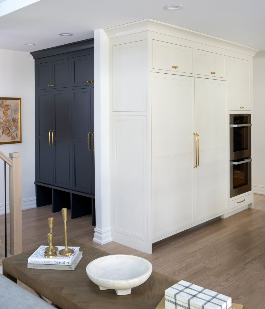Large transitional galley medium tone wood floor, brown floor and shiplap ceiling open concept kitchen photo in Philadelphia with a farmhouse sink, flat-panel cabinets, white cabinets, quartz countertops, white backsplash, porcelain backsplash, paneled appliances, an island and white countertops