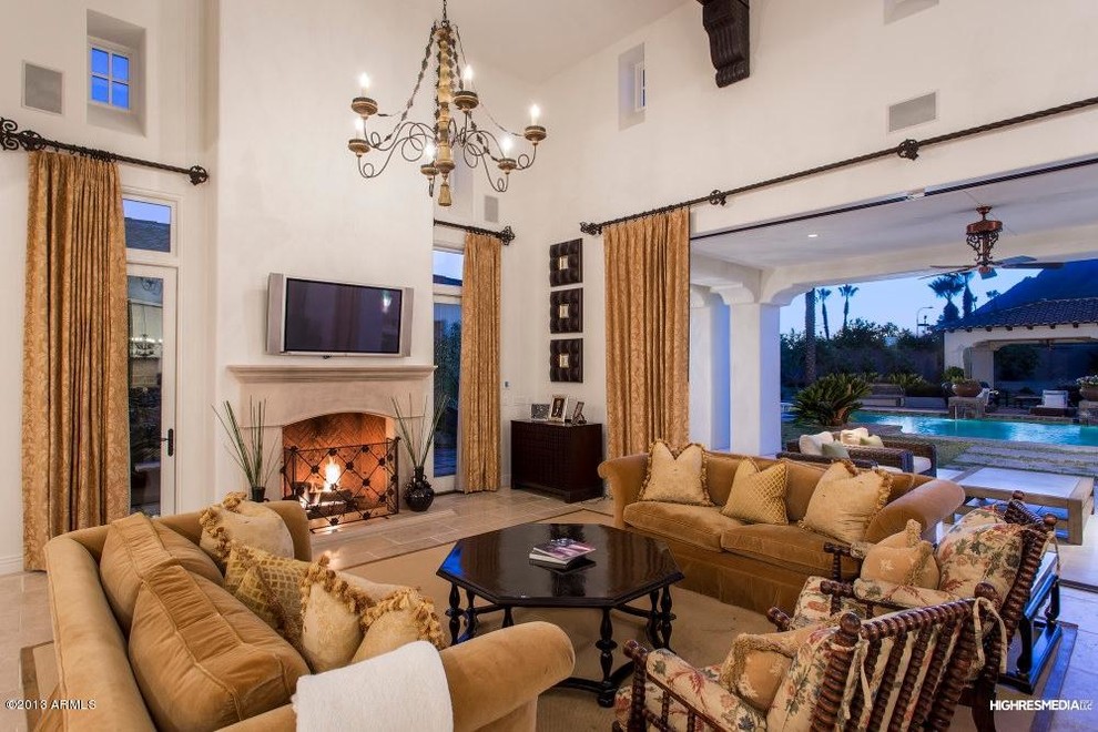 Inspiration for an expansive mediterranean open concept living room in Phoenix with beige walls, a standard fireplace, a wood fireplace surround, a wall-mounted tv and red floor.