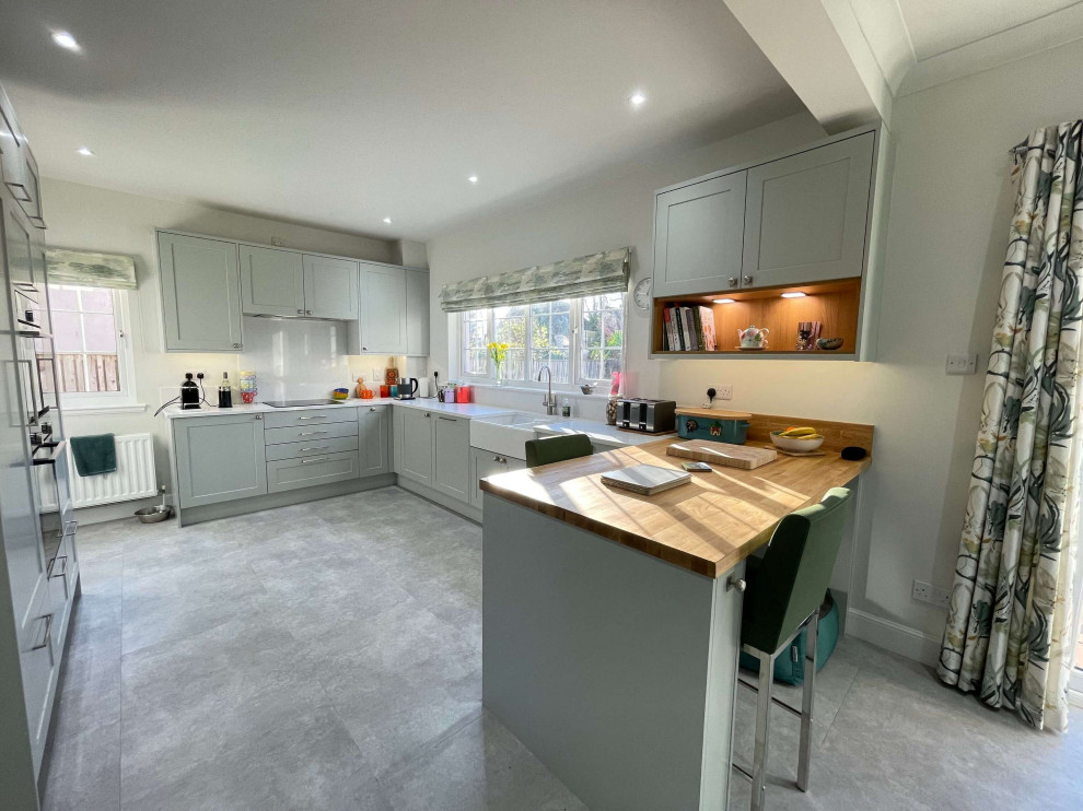 Photo of a medium sized classic u-shaped open plan kitchen with shaker cabinets, grey cabinets, quartz worktops, a breakfast bar, grey floors and white worktops.